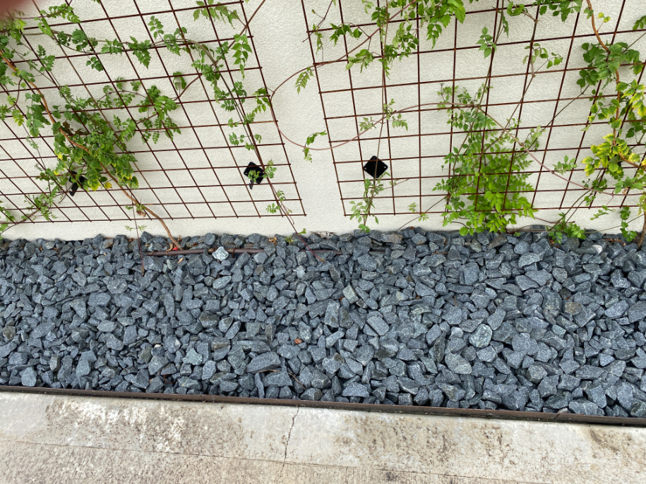 Black Granite decorative landscape gravel with steel edging and a lattice with ivy located in Kansas City