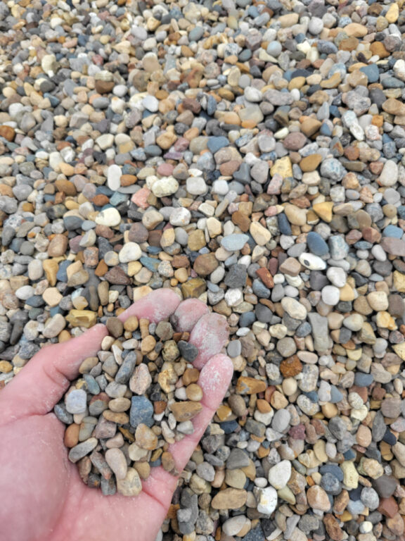 Close up photo of Missouri Rainbow Pea Gravel in the palm of a hand for size reference