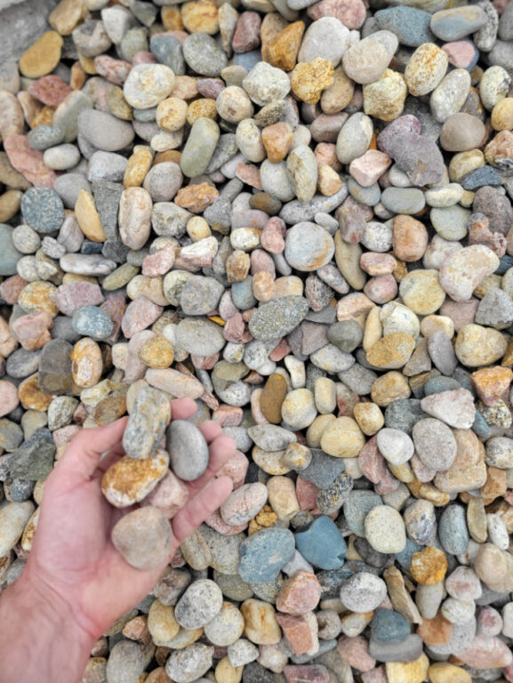 close up photo of multi colored cobblestone in the palm of a hand