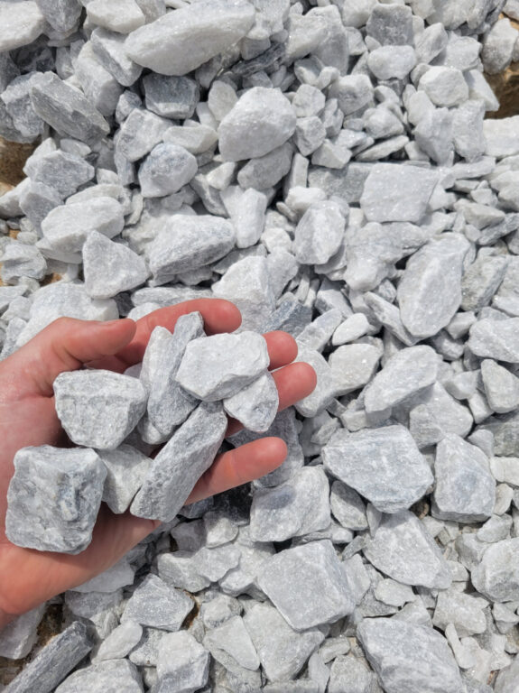 Close up photo of White Marble landscape rock in the palm of a hand. Available in bags or bulk for pickup or delivery in Kansas City