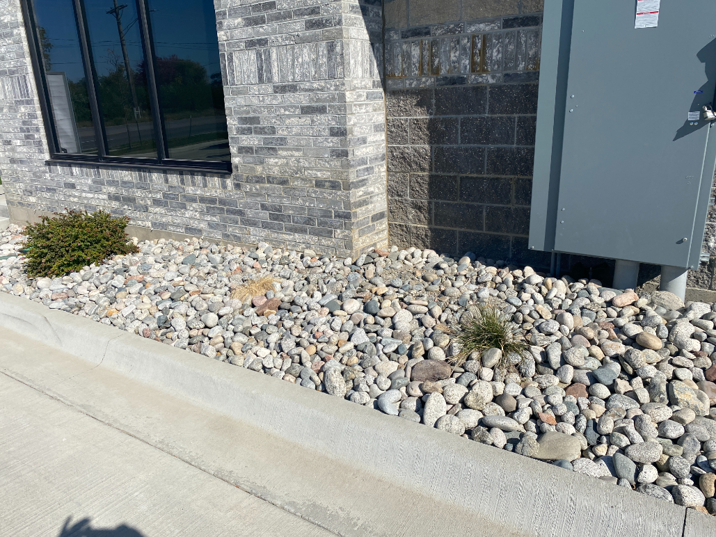 Gray Cobblestone next to a similarly colored building in a landscape bed