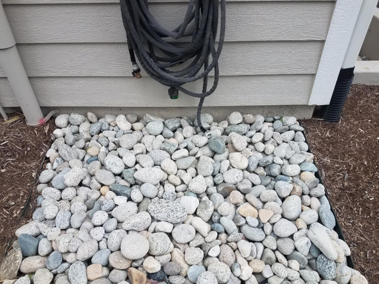 2-4" Gray Cobblestone used near a hose and downspout area to distribute waterflow