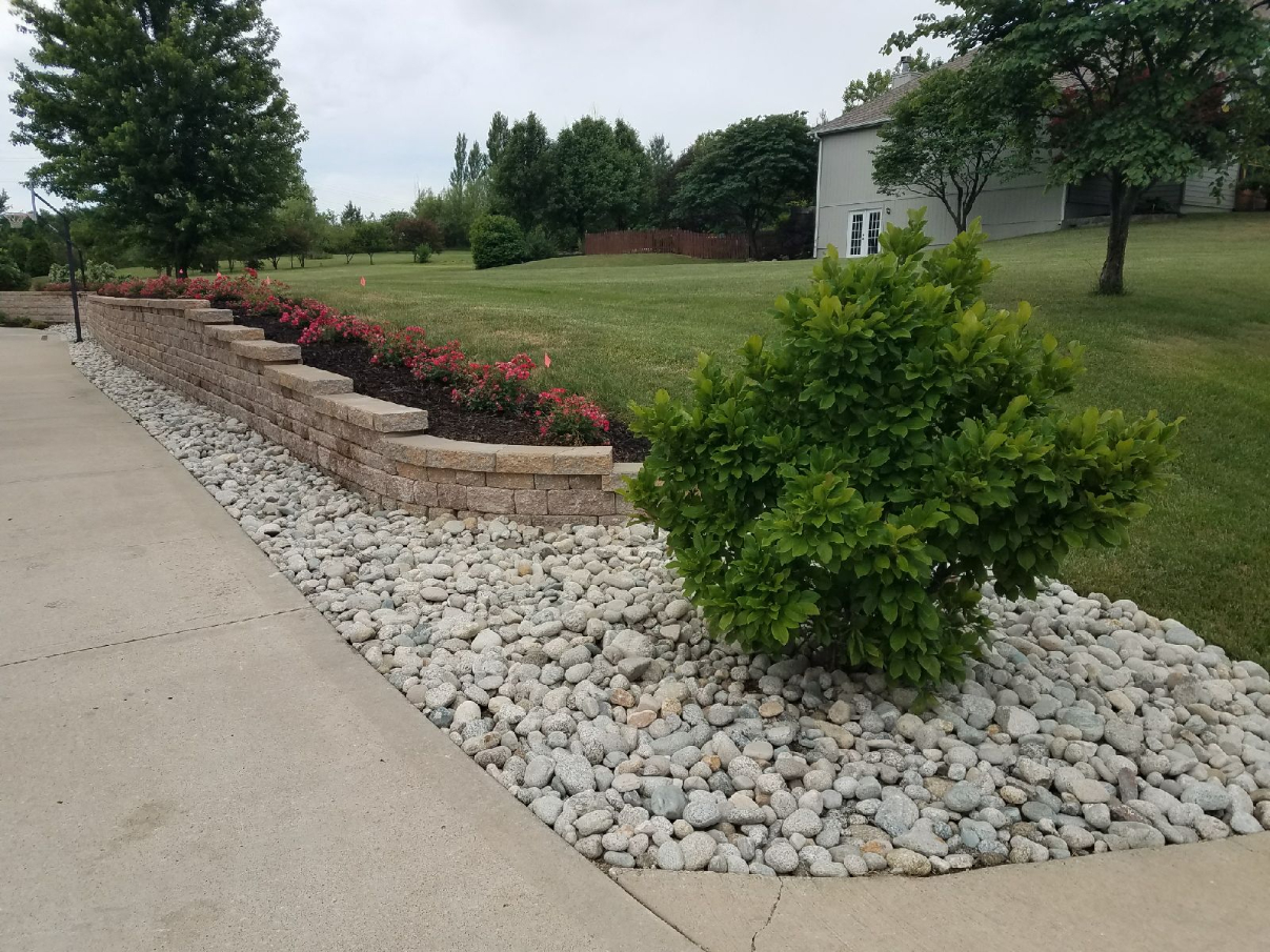 Gray cobblestone next to a driveway with a large bush in Kansas City
