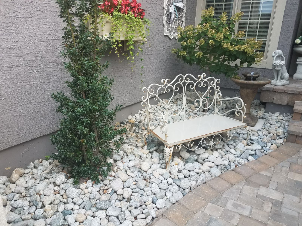 Gray cobble in a landscape bed with a bench and bushes