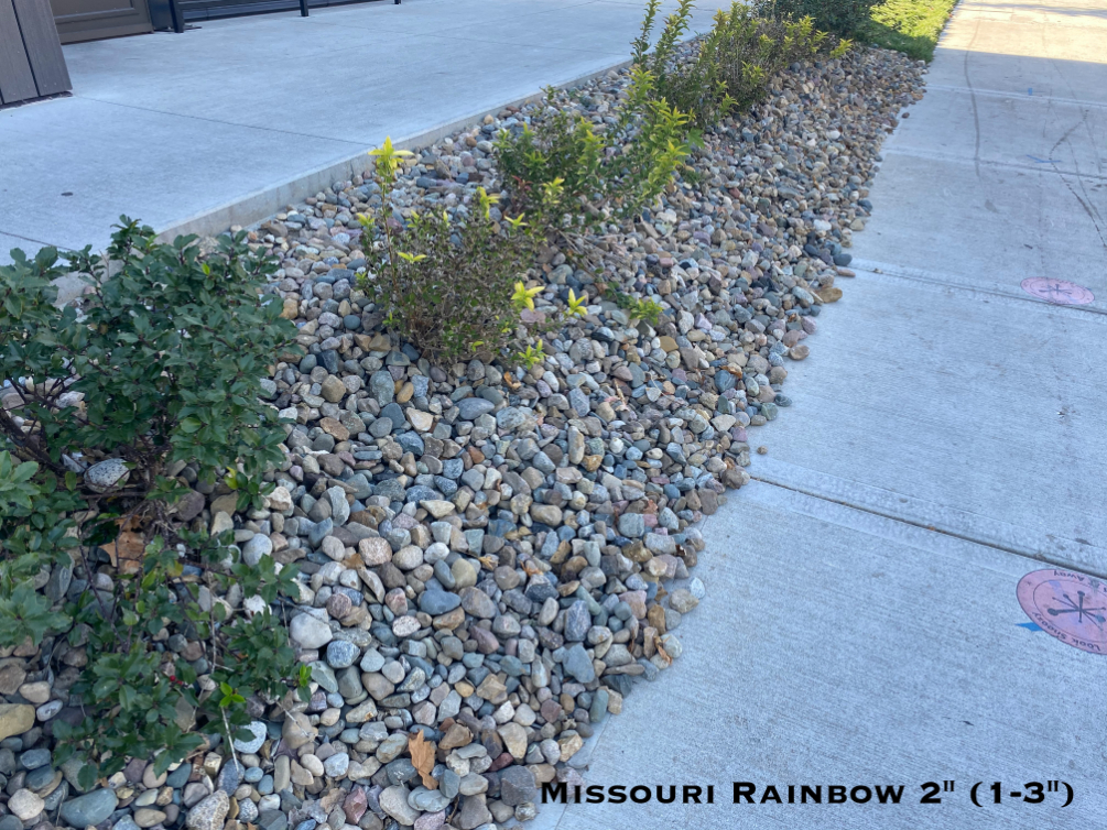 Missouri Rainbow River Rock used in a landscape bed with shrubs located in Kansas City