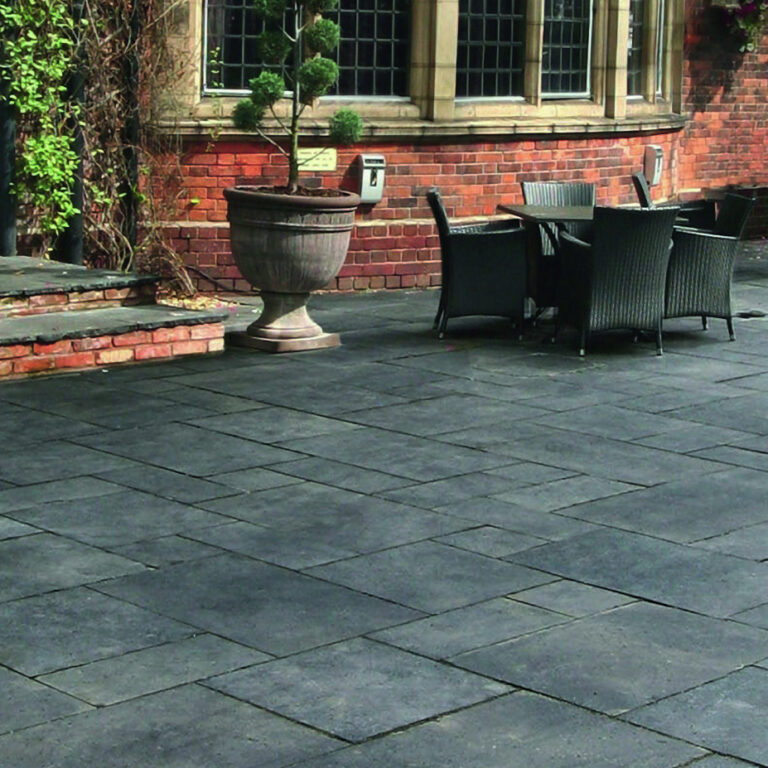 Charcoal Natural Stone Paving in a patio area with a red brick home