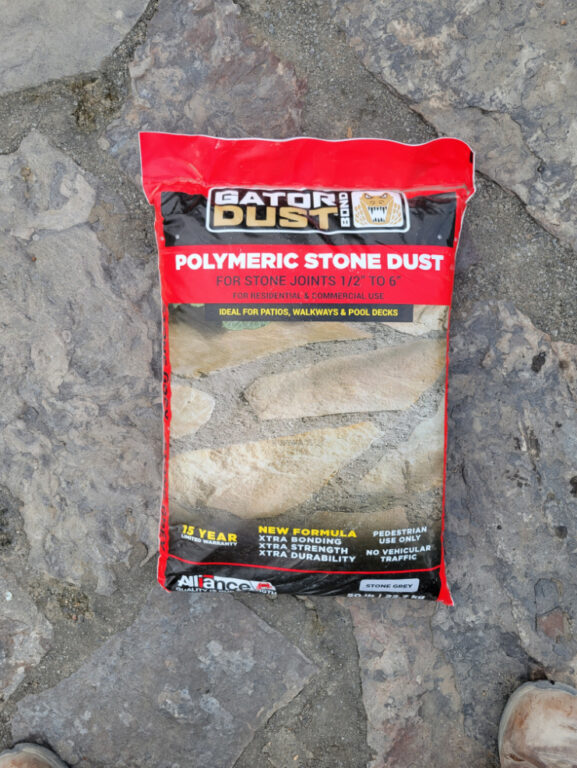 Close up bag of Gator Dust Polymeric Stone Dust on a flagstone patio.